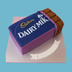 A novelty cake designed to look like a Cadbury Dairy Milk chocolate bar, featuring smooth purple fondant that mimics the iconic packaging. The top displays the detailed Dairy Milk logo alongside a glossy, raised chocolate bar section with realistic square segments. A fondant banner at the base holds a personalized message space. The cake’s vibrant colors and realistic design make it an eye-catching centerpiece for birthdays or special occasions, especially for chocolate lovers.